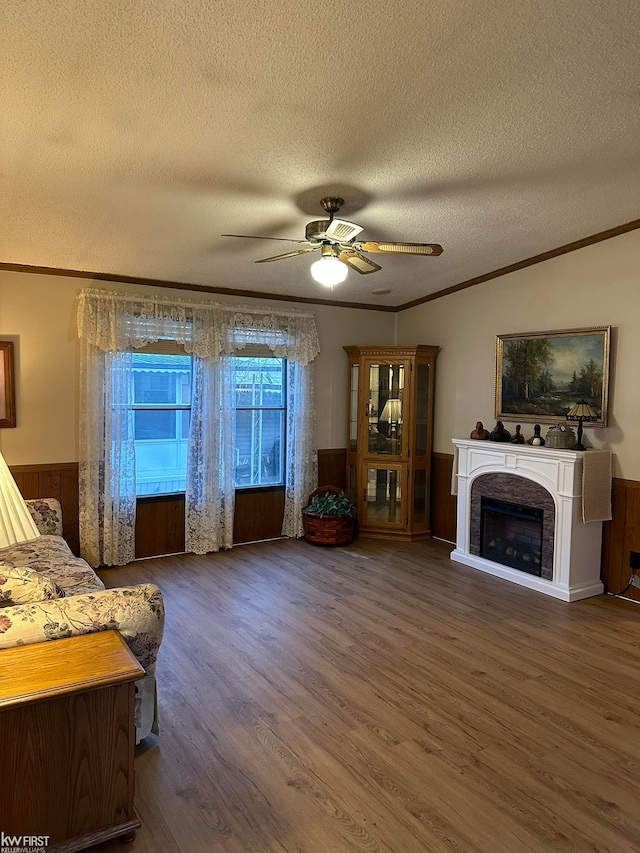 living room with dark hardwood / wood-style flooring, ornamental molding, a textured ceiling, ceiling fan, and wood walls