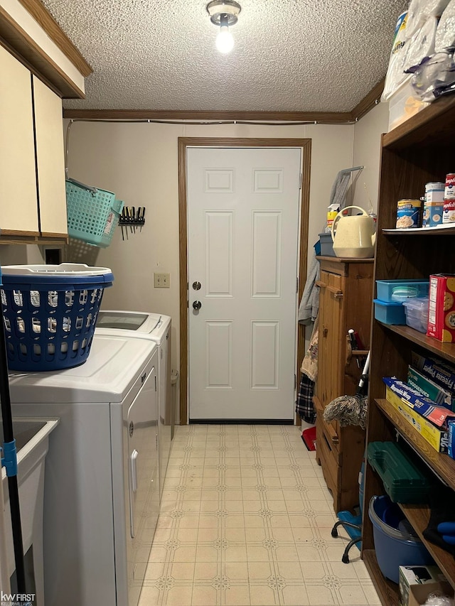 clothes washing area featuring washer and clothes dryer, crown molding, cabinets, and a textured ceiling