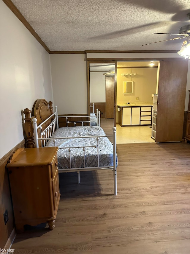 bedroom with hardwood / wood-style floors, a textured ceiling, ceiling fan, and crown molding