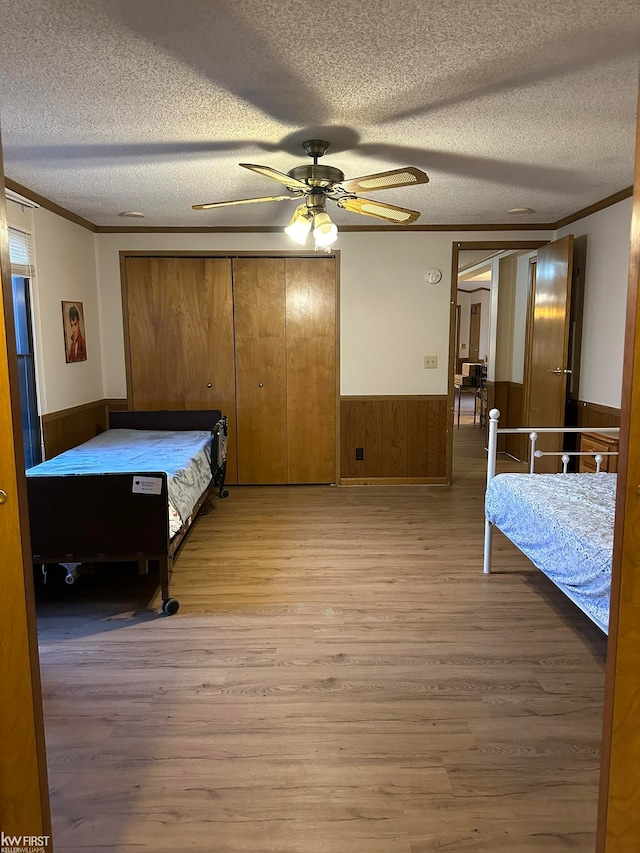 bedroom featuring light hardwood / wood-style floors, crown molding, and a textured ceiling