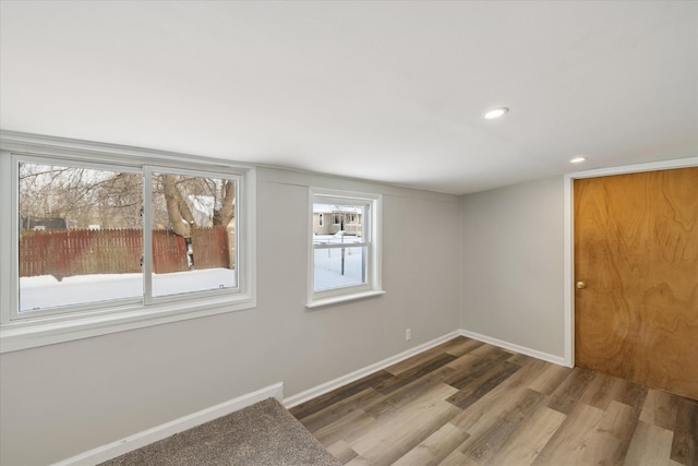 spare room with baseboards, wood finished floors, and recessed lighting