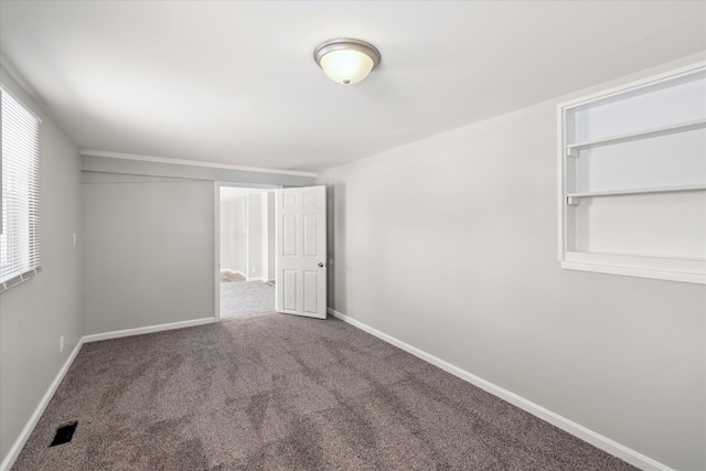 carpeted spare room featuring visible vents and baseboards