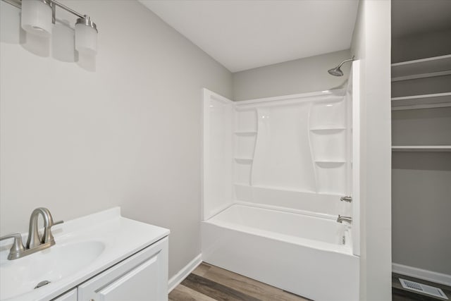 bathroom with wood finished floors, visible vents, vanity, baseboards, and  shower combination