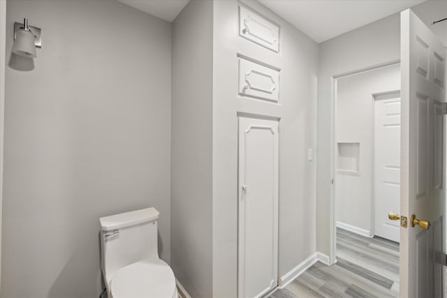 bathroom with toilet, baseboards, and wood finished floors