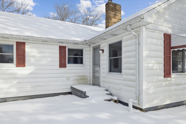 view of snowy exterior featuring a chimney