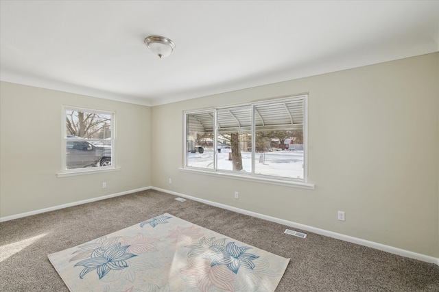 unfurnished room featuring a wealth of natural light, carpet, visible vents, and baseboards