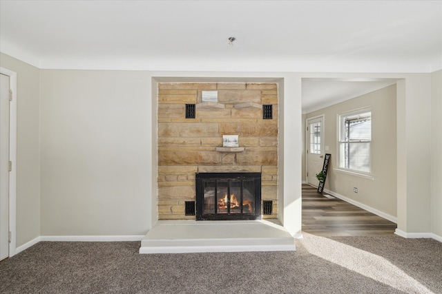 unfurnished living room featuring carpet, a fireplace, and baseboards