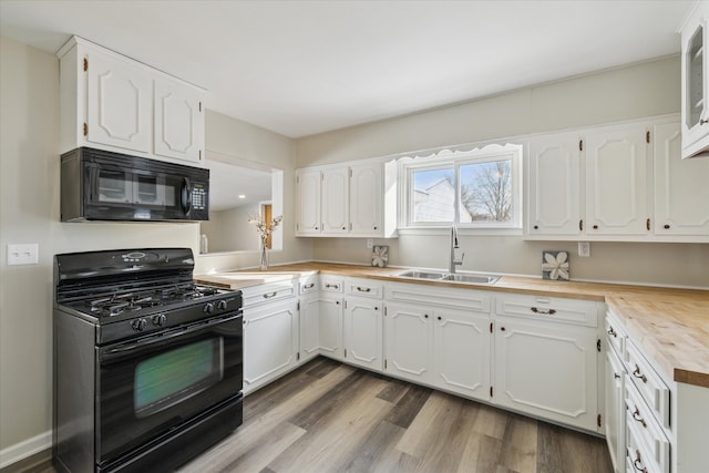 kitchen with dark wood-style flooring, a sink, wood counters, white cabinetry, and black appliances