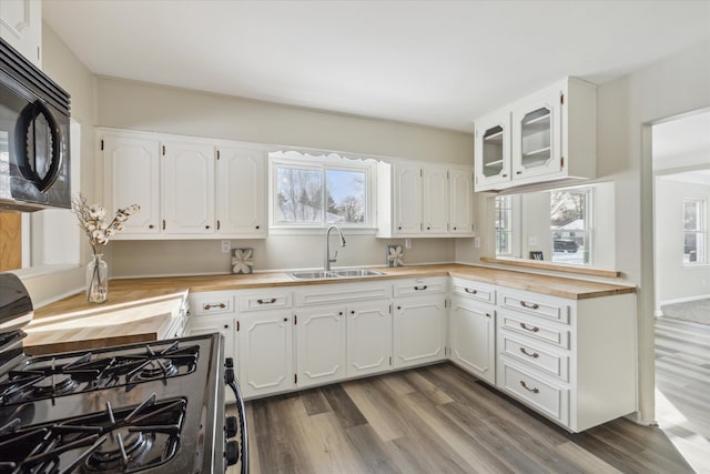 kitchen with black appliances, dark wood finished floors, white cabinets, and a sink