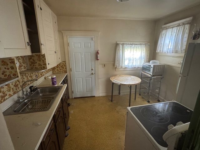 kitchen featuring range, white cabinets, white refrigerator, sink, and dark brown cabinetry