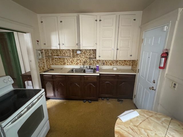 kitchen with tasteful backsplash, dark brown cabinets, sink, white electric stove, and white cabinets