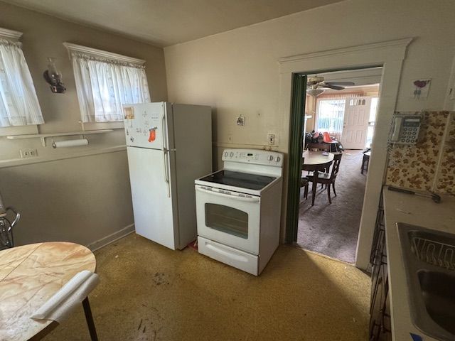 kitchen with ceiling fan, light colored carpet, white appliances, and sink