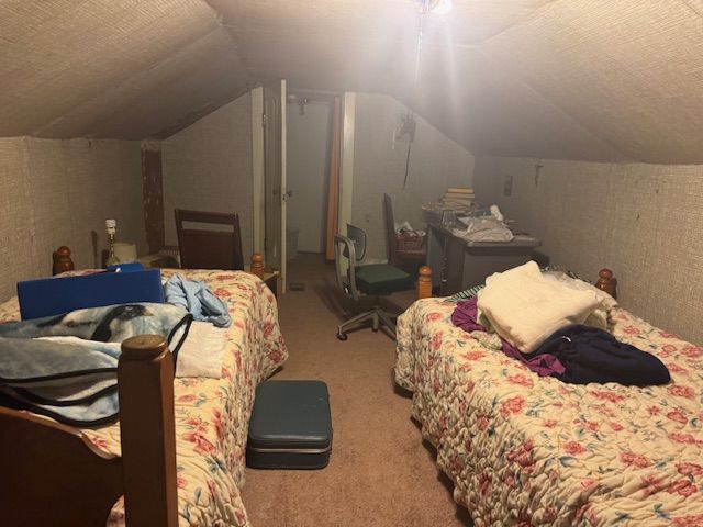 bedroom with a textured ceiling, carpet floors, and vaulted ceiling