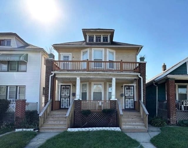 view of front of house featuring a balcony, covered porch, and a front yard