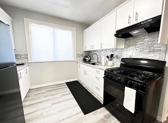 kitchen featuring sink, stainless steel fridge, white cabinetry, tasteful backsplash, and black range with gas stovetop