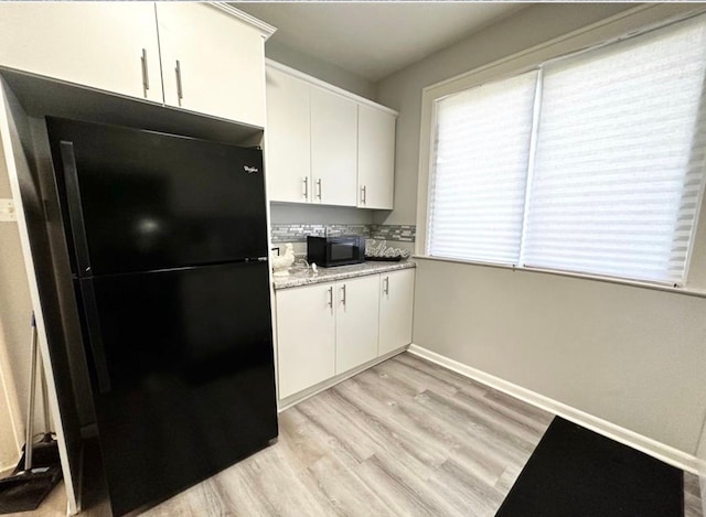 kitchen featuring light stone countertops, black appliances, light hardwood / wood-style floors, and white cabinets