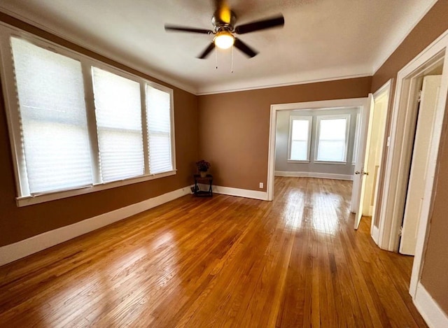 empty room with ornamental molding, hardwood / wood-style floors, and ceiling fan