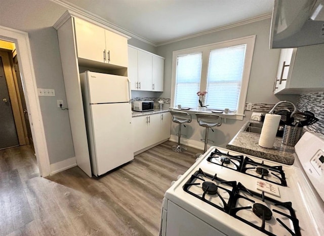 kitchen featuring white cabinetry, wood-type flooring, ornamental molding, white appliances, and decorative backsplash