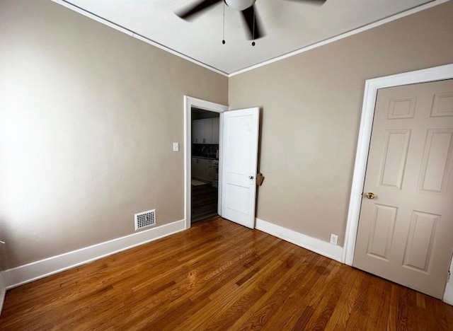 unfurnished bedroom with hardwood / wood-style flooring, ornamental molding, and ceiling fan