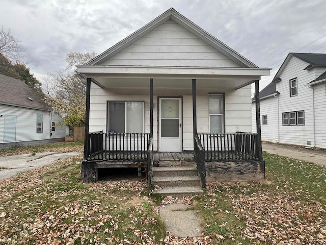 bungalow-style home with covered porch and a front lawn