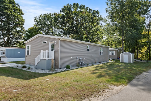 view of side of home featuring central AC unit, a storage shed, and a lawn