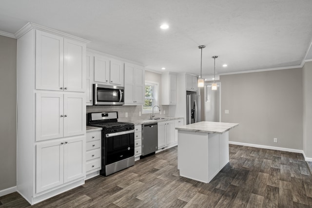 kitchen with appliances with stainless steel finishes, sink, decorative light fixtures, white cabinets, and a kitchen island