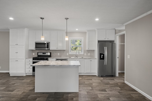 kitchen featuring white cabinetry, sink, stainless steel appliances, crown molding, and decorative light fixtures