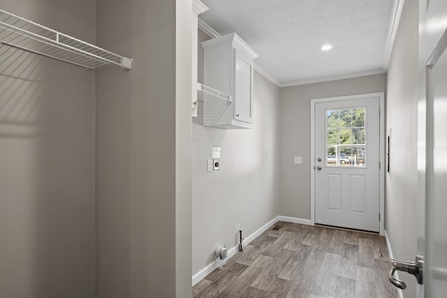 laundry room with hookup for an electric dryer, light hardwood / wood-style floors, cabinets, and crown molding