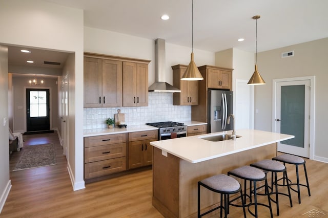 kitchen featuring light hardwood / wood-style floors, wall chimney range hood, sink, and appliances with stainless steel finishes