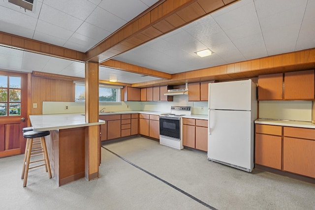 kitchen featuring a kitchen bar, white appliances, light colored carpet, and extractor fan