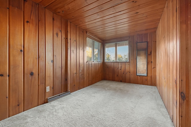 carpeted spare room with wood walls and wooden ceiling