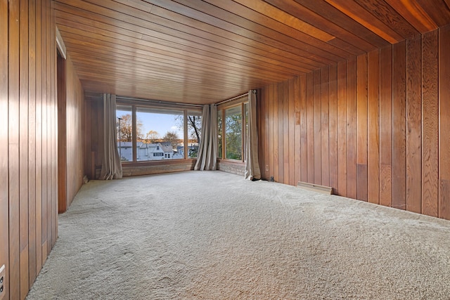 carpeted spare room with wood walls and wood ceiling