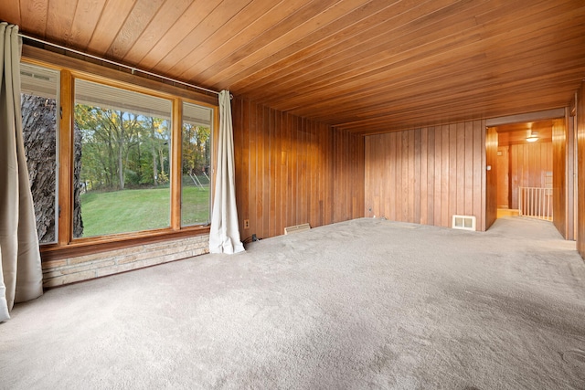 spare room featuring carpet floors, wooden walls, and wood ceiling