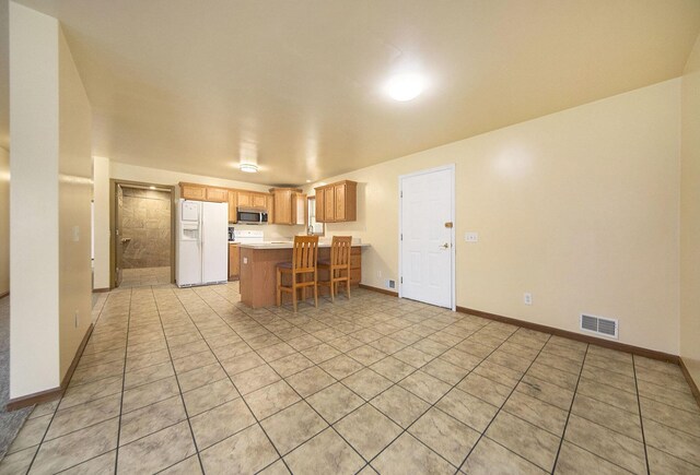 10376 Glencoe Rd, Jerome, MI 49249 - kitchen with white fridge with ice dispenser, stainless steel microwave, a peninsula, light countertops, and light tile patterned flooring