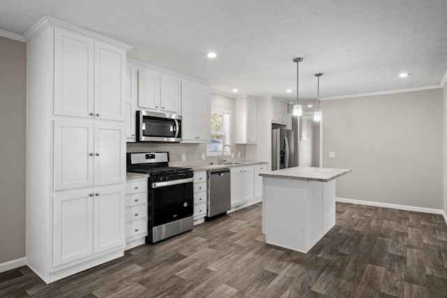 kitchen with a center island, white cabinets, sink, hanging light fixtures, and appliances with stainless steel finishes