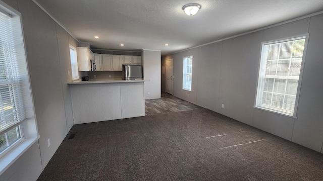 875 W Grand River Ave Unit 35, Williamston, MI 48895 - kitchen with stainless steel appliances, ornamental molding, carpet floors, light countertops, and a peninsula