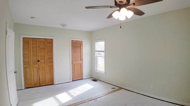 unfurnished bedroom with multiple closets and ceiling fan