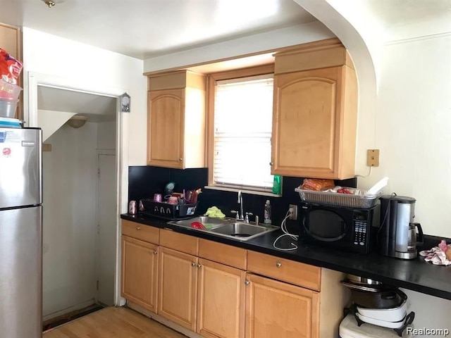 kitchen featuring light brown cabinets, light wood-type flooring, sink, and stainless steel refrigerator