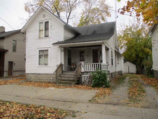 bungalow-style house featuring a porch and a storage shed