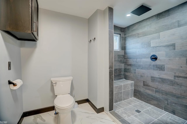 bathroom with a tile shower and toilet