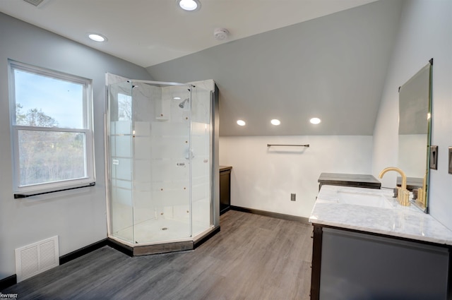 bathroom featuring hardwood / wood-style floors, vanity, lofted ceiling, and walk in shower