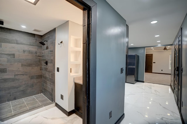 bathroom featuring tiled shower, vanity, and built in features