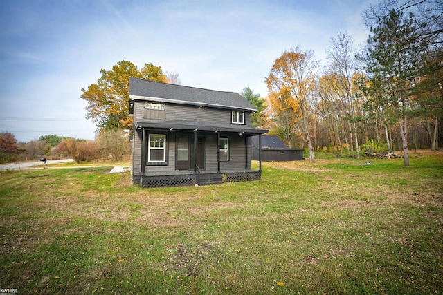 rear view of house featuring a lawn and covered porch