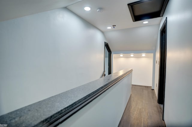 corridor featuring wood-type flooring and vaulted ceiling