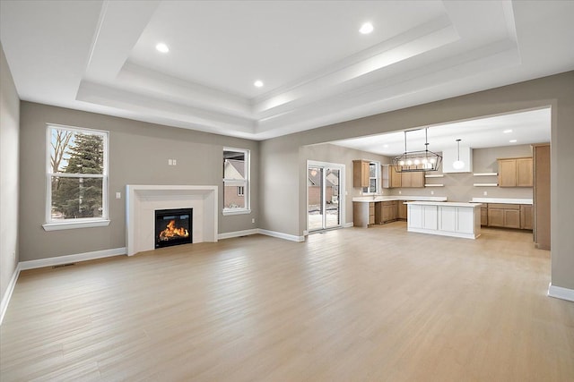 unfurnished living room with a tray ceiling and light hardwood / wood-style floors