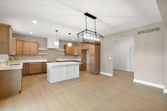 kitchen with a chandelier, a center island, light hardwood / wood-style floors, and sink