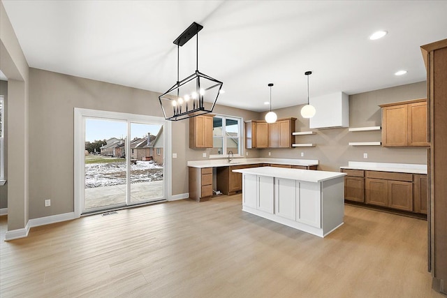 kitchen featuring sink, pendant lighting, light hardwood / wood-style flooring, a chandelier, and a center island