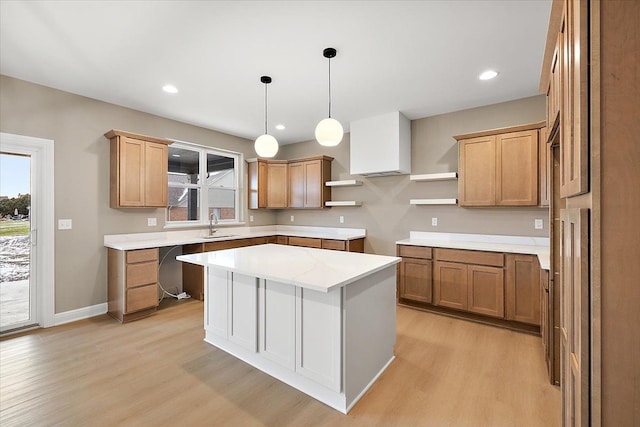 kitchen featuring sink, a center island, dishwasher, pendant lighting, and light wood-type flooring