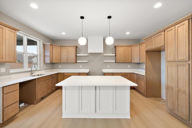 kitchen featuring a kitchen island, sink, hanging light fixtures, and light hardwood / wood-style flooring