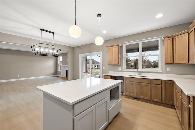 kitchen with pendant lighting, sink, light wood-type flooring, a notable chandelier, and a kitchen island